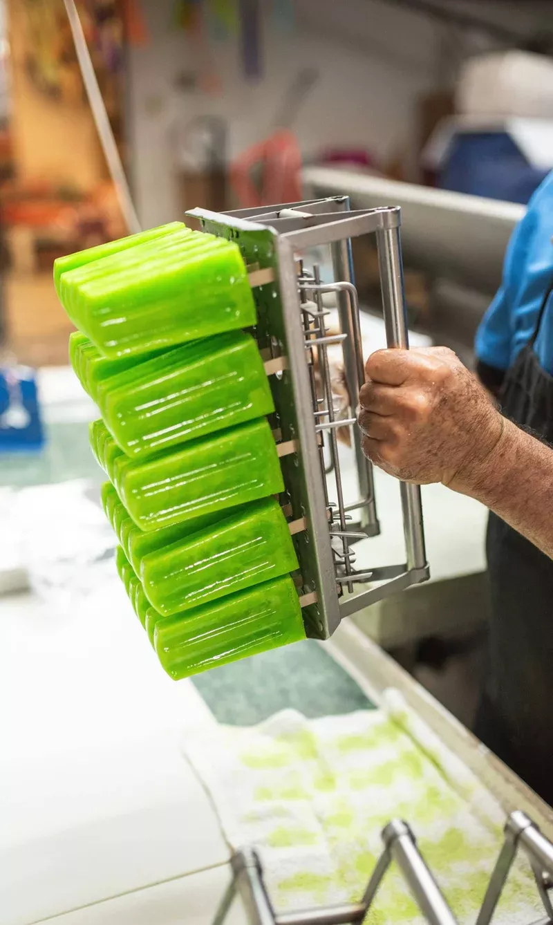Handmade green paletas on a paleta-making device.